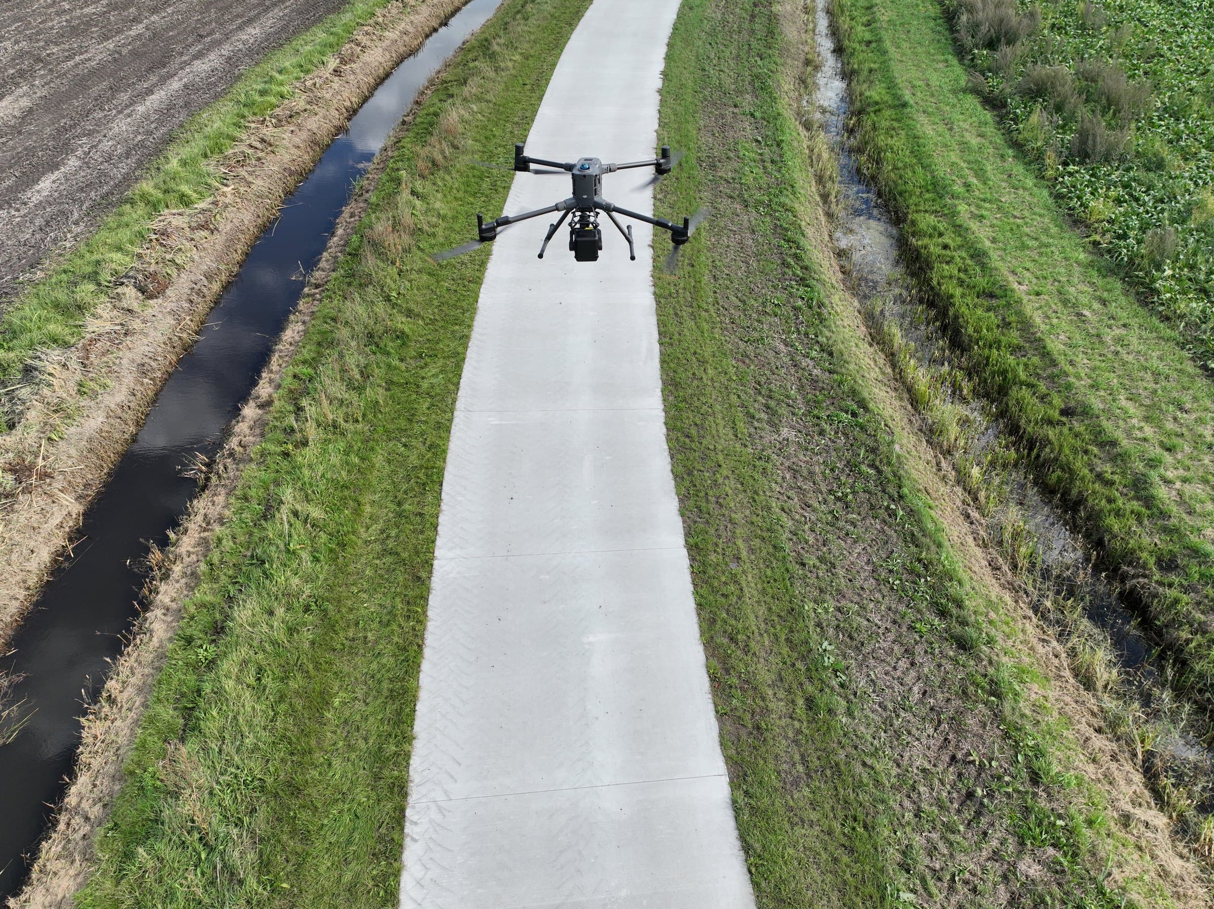 Meetvlucht met de DJI Matrice 400 en Zenmuse L3 boven een pas aangelegde betonweg, met sloot en perceel aan weerszijden
